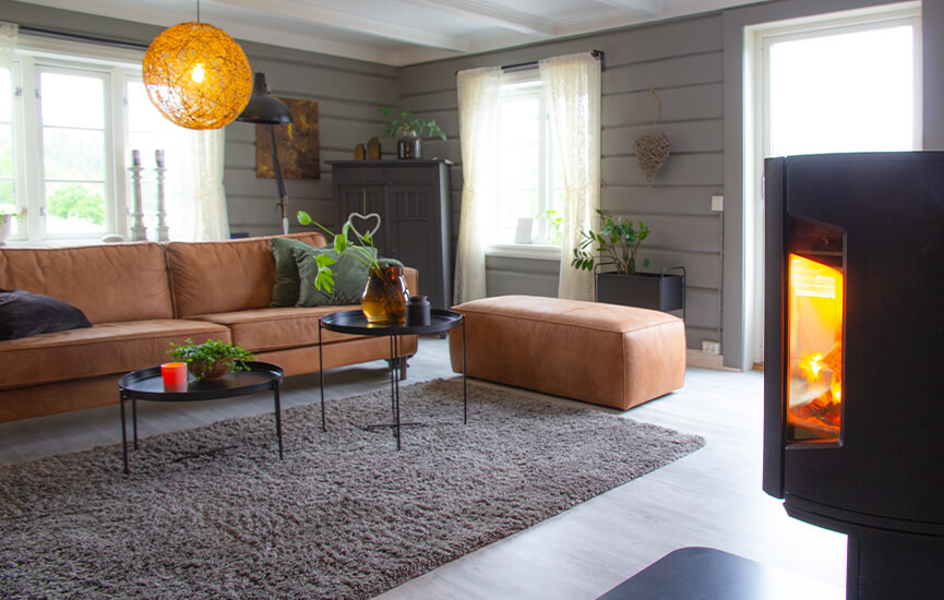 Houtkachel in grijze woonkamer met houten muren en bruine bank