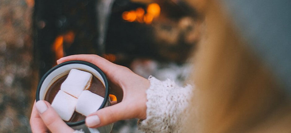 Meisje drinkt cacao bij het vuur