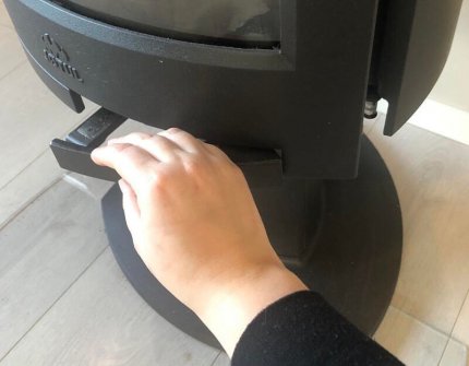 Hand die de haarddeur naar de houtkachel opent Jøtul F 373 Voorzichtig vooruit