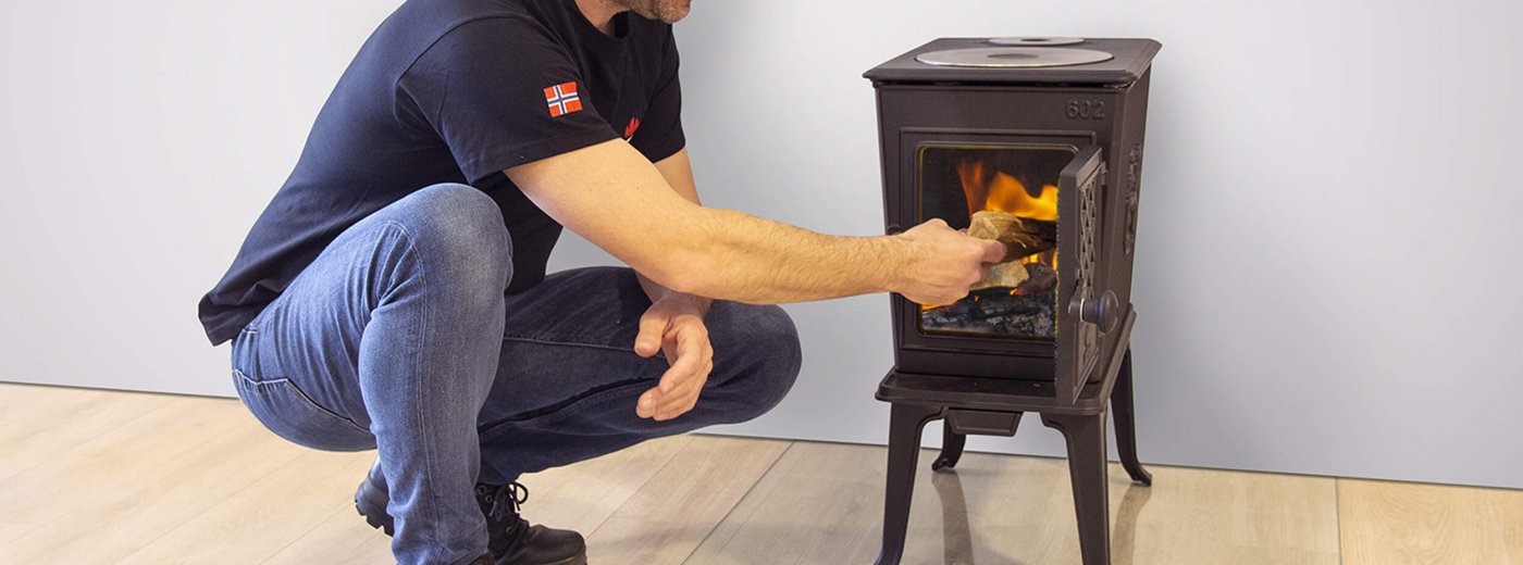 Een man doet hout in de Jøtul F 602 ECO houtkachel