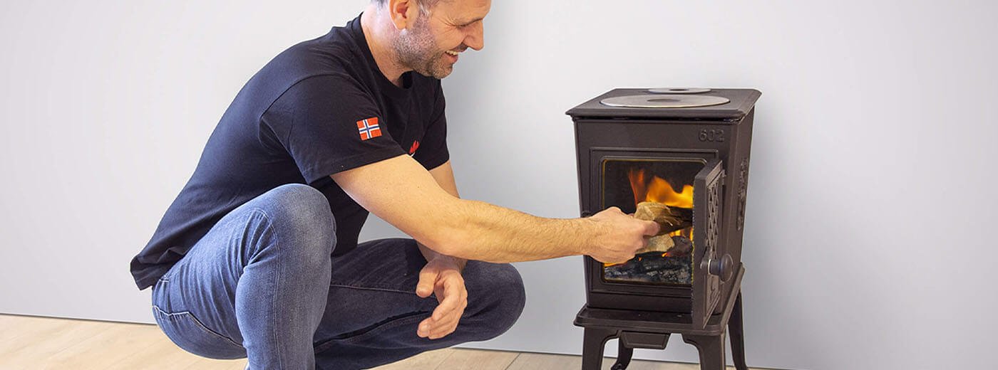 man stopt hout in de Jøtul F 602 houtkachel