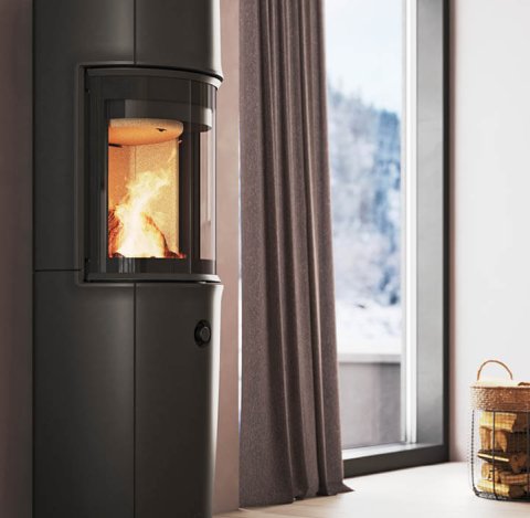 Moderne kamer met grote zwarte Jøtul F 176 houtkachel, poederpaarse muren en uitzicht op de besneeuwde bergen